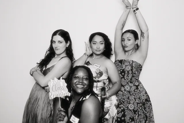 Guests laughing in a black and white photo booth portrait.