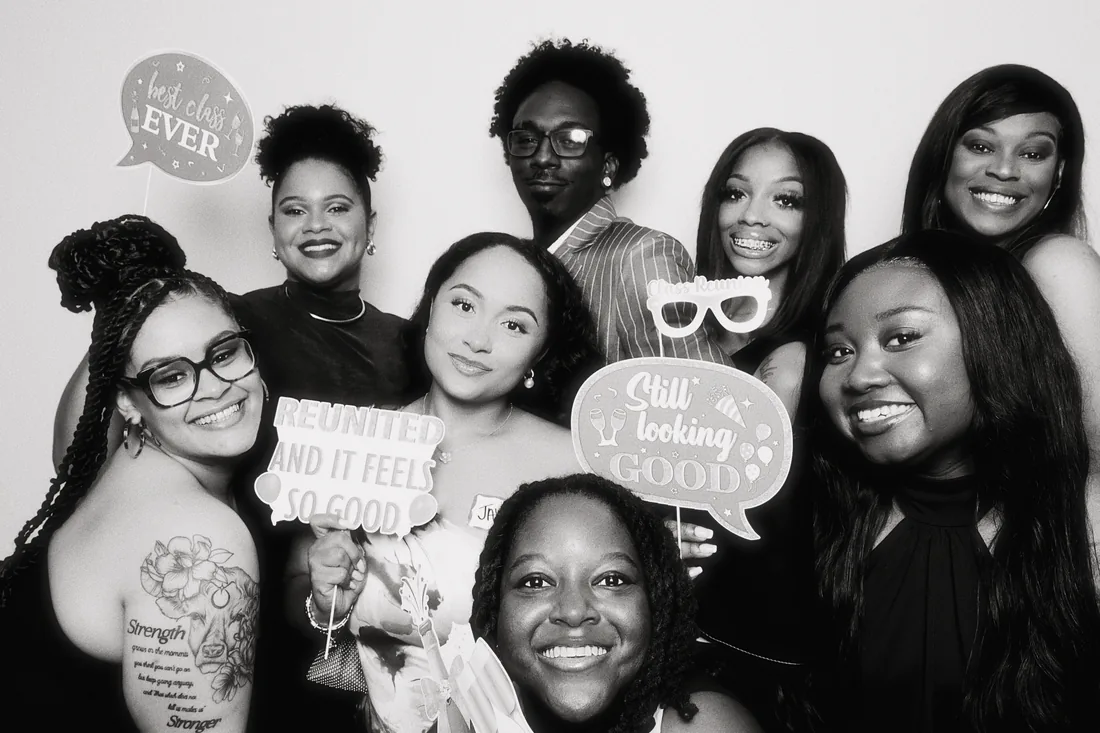 Guests holding prop signs in a black and white booth photo.