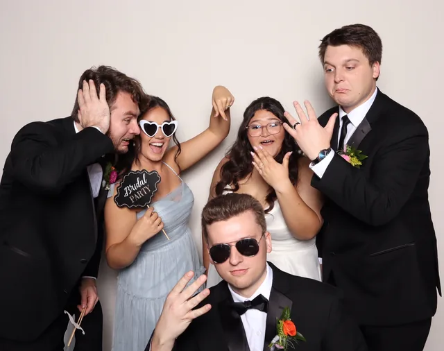 Bride and her bridal party goofing off in the booth, one guest holding a Bridal Party sign.