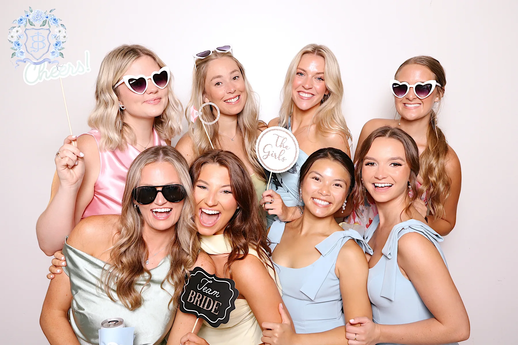 A group of guests posed together with props in the booth, under a custom photo overlay.